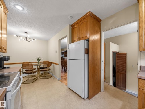 Kitchen area with oak-finish cabinetry, light-toned vinyl flooring, and a recessed ceiling light - 18416 90 Avenue, Edmonton, AB 