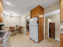 Kitchen area with oak-finish cabinetry, light-toned vinyl flooring, and a recessed ceiling light - 
