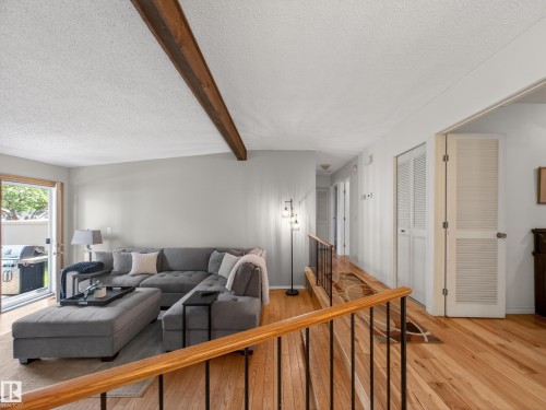Bright living area featuring wood-finish flooring and a prominent exposed beam ceiling - 18416 90 Avenue, Edmonton, AB 