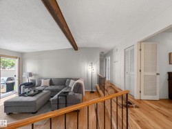 Bright living area featuring wood-finish flooring and a prominent exposed beam ceiling - 