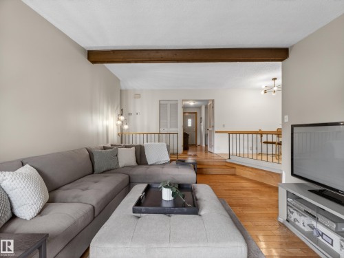 Living area featuring wood-finish flooring, a recessed ceiling, and an exposed wood beam - 18416 90 Avenue, Edmonton, AB 