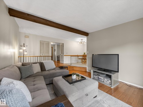Living area with wood-finish flooring and a wood ceiling beam - 18416 90 Avenue, Edmonton, AB 