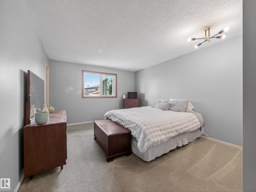 Bedroom featuring light gray wall paint, a double-paned window with wood trim, and a modern sputnik-style ceiling light fixture - 18416 90 Avenue, Edmonton, AB 