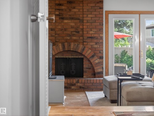 Brick fireplace featuring an arched firebox opening and dark metal screen - 18416 90 Avenue, Edmonton, AB 