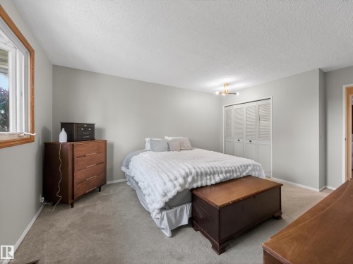 Neutral wall paint, carpet flooring, a window with wood trim, and bi-fold closet doors - 18416 90 Avenue, Edmonton, AB 