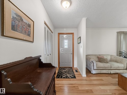 Entryway featuring light wood-finish flooring, white paneled door with decorative glass inserts, and louvered bifold closet doors - 18416 90 Avenue, Edmonton, AB 