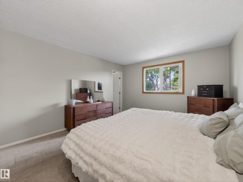 Carpeted room featuring light gray wall paint, a window with wood trim, and a textured ceiling - 18416 90 Avenue, Edmonton, AB 