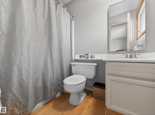 Full bathroom featuring a single vanity with a white countertop and light-colored cabinetry, a white toilet, and light wood-finish flooring - 18416 90 Avenue, Edmonton, AB 