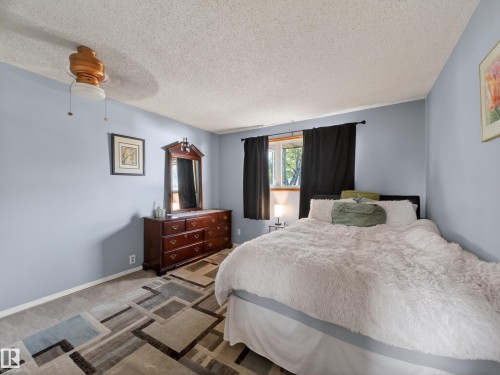 Spacious room featuring a ceiling fan with integrated lighting, a window with dark curtains, and a patterned carpet flooring - 18416 90 Avenue, Edmonton, AB 