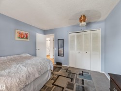 Bedroom featuring textured carpet flooring, bi-fold louvered closet doors, and a ceiling fan with integrated lighting - 