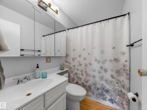 Bathroom featuring a white vanity with integrated sink, chrome faucet, and a large mirrored medicine cabinet - 18416 90 Avenue, Edmonton, AB 