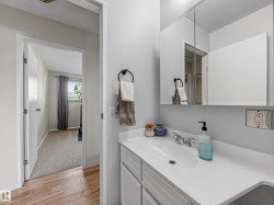 Bathroom vanity featuring a white countertop with integrated sink, chrome faucet, and a wall-mounted medicine cabinet with mirrored doors - 
