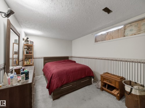 Bedroom featuring a wood-finish bed frame, light gray carpeting, and white walls with a striped lower panel - 18416 90 Avenue, Edmonton, AB 