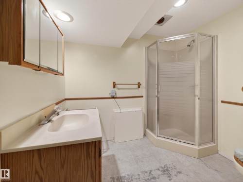 Bathroom featuring a corner shower enclosure, a vanity with a built-in sink, and a mirrored medicine cabinet - 18416 90 Avenue, Edmonton, AB 