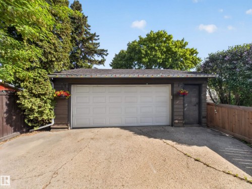 Detached garage with a white panel door, separate exterior access door, and dark siding - 18416 90 Avenue, Edmonton, AB 