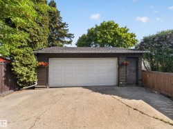 Detached garage with a white panel door, separate exterior access door, and dark siding - 