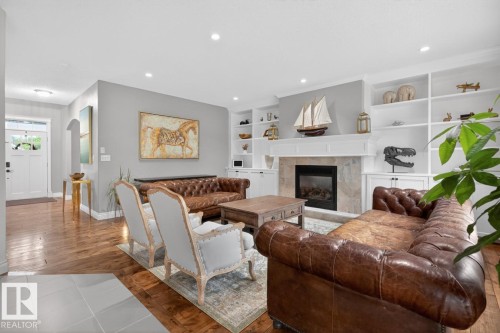 Large Living Room featuring Gas Fireplace, South West Facing Windows, and built in Shelving/Cabinets - 5016 213 Street, Edmonton, AB 