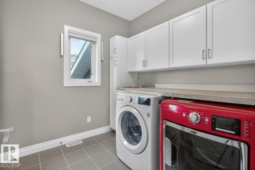 Main Floor Laundry area featuring Cabinetry, Laundry Sink, and Counter Space - 5016 213 Street, Edmonton, AB 