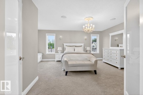 Spacious Primary Bedroom featuring Double French Doors, South West Facing Corner Windows, Built in Window Bench with additional Storage, Large Walk in Closet, and 5 Piece Ensuite with Heated Floors - 5016 213 Street, Edmonton, AB 