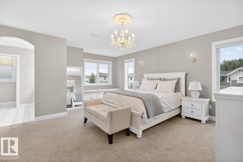 Spacious Primary Bedroom featuring Double French Doors, South West Facing Corner Windows, Built in Window Bench with additional Storage, Large Walk in Closet, and 5 Piece Ensuite with Heated Floors - 5016 213 Street, Edmonton, AB 