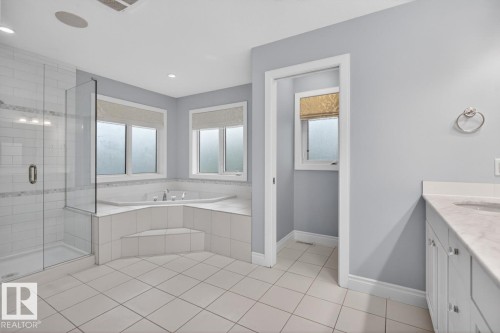 Spacious bathroom featuring a corner soaking tub, glass shower, heated flooring, double vanity, and separate water closet - 5016 213 Street, Edmonton, AB 