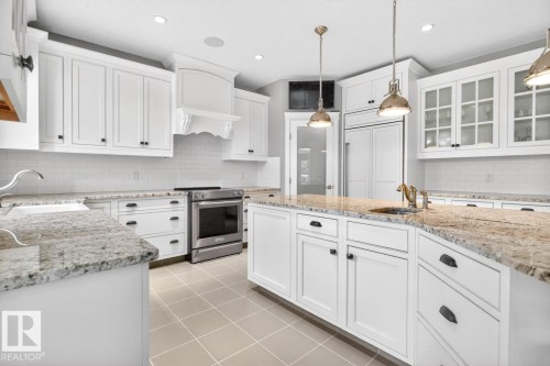 Large White Cabinet Kitchen featuring Granite Counters, Sub-Zero Refrigerator, Dishwasher (2025), Garburator (2025), Electric Stove (2026), Large Walk Through Pantry, and Prep Sink in Island - 5016 213 Street, Edmonton, AB 