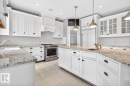 Large White Cabinet Kitchen featuring Granite Counters, Sub-Zero Refrigerator, Dishwasher (2025), Garburator (2025), Electric Stove (2026), Large Walk Through Pantry, and Prep Sink in Island - 5016 213 Street, Edmonton, AB 