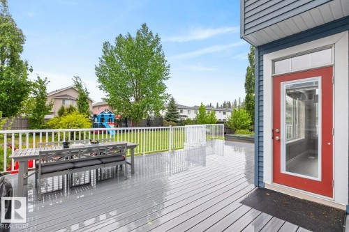 Spacious outdoor deck featuring hot tub (included), gray composite decking and white railing - 5016 213 Street, Edmonton, AB 