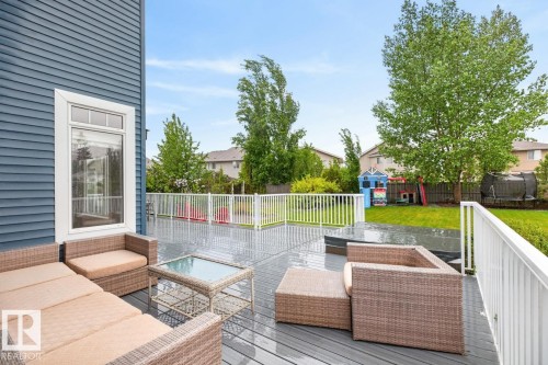 Spacious outdoor deck featuring hot tub (included), gray composite decking and white railing - 5016 213 Street, Edmonton, AB 