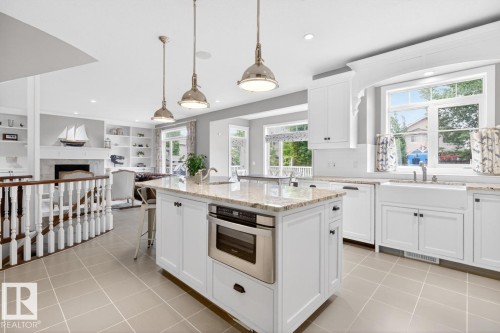 Large White Cabinet Kitchen featuring Granite Counters, Sub-Zero Refrigerator, Dishwasher (2025), Garburator (2025), Electric Stove (2026), Large Walk Through Pantry, and Prep Sink in Island - 5016 213 Street, Edmonton, AB 