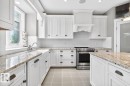 Large White Cabinet Kitchen featuring Granite Counters, Sub-Zero Refrigerator, Dishwasher (2025), Garburator (2025), Electric Stove (2026), Large Walk Through Pantry, and Prep Sink in Island - 5016 213 Street, Edmonton, AB 