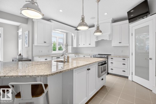 Large White Cabinet Kitchen featuring Granite Counters, Sub-Zero Refrigerator, Dishwasher (2025), Garburator (2025), Electric Stove (2026), Large Walk Through Pantry, and Prep Sink in Island - 5016 213 Street, Edmonton, AB 