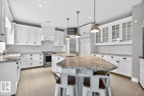 Large White Cabinet Kitchen featuring Granite Counters, Sub-Zero Refrigerator, Dishwasher (2025), Garburator (2025), Electric Stove (2026), Large Walk Through Pantry, and Prep Sink in Island - 5016 213 Street, Edmonton, AB 