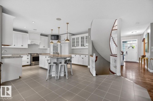 Large White Cabinet Kitchen featuring Granite Counters, Sub-Zero Refrigerator, Dishwasher (2025), Garburator (2025), Electric Stove (2026), Large Walk Through Pantry, and Prep Sink in Island - 5016 213 Street, Edmonton, AB 