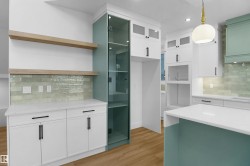 Modern kitchen featuring white cabinetry, a light blue-green island base, and a matching full-height glass-front pantry - 