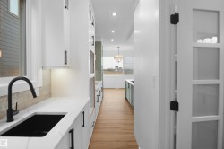 Modern kitchen prep area featuring a black basin sink, matte black faucet, and white countertop - 