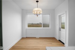 Room featuring wood-finish flooring, white baseboards, and a contemporary chandelier - 