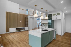 Open-concept interior featuring wood-finish flooring, a kitchen island with a white countertop and dark sink, and pendant lighting - 
