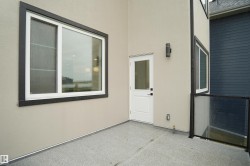 Outdoor patio area featuring a white door, large window with dark trim, and a glass railing - 