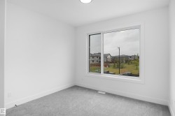 Interior room featuring a large window, light gray carpeting, white walls, white baseboards, and a ceiling-mounted light fixture - 