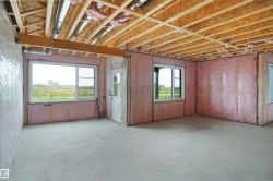 Unfinished lower level featuring exposed wood joists and subflooring, insulated walls, and a concrete floor - 
