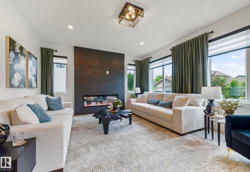 Contemporary living space featuring an electric fireplace with a dark, veined stone surround - 16607 8 Street, Edmonton, AB 