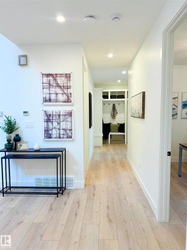 Bright hallway with wood-finish flooring, recessed lighting, white walls, and a built-in bench with cubbies - 16607 8 Street, Edmonton, AB 