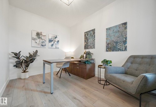 Bright room featuring light wood-finish flooring, white walls, and a modern ceiling light fixture - 16607 8 Street, Edmonton, AB 