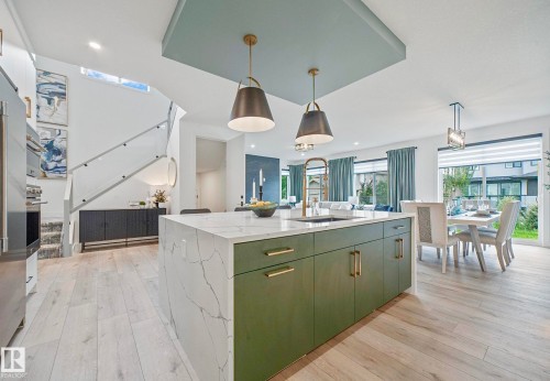 Central kitchen island with waterfall countertop, integrated sink, and pendant lighting - 16607 8 Street, Edmonton, AB 