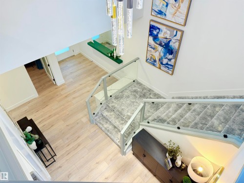 Multi-level interior featuring a contemporary glass and metal staircase with textured carpet runners, light wood-finish flooring, and a two-story ceiling - 16607 8 Street, Edmonton, AB 