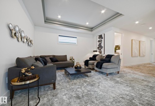 Recessed lighting illuminates this space featuring a multi-tiered tray ceiling, plush carpeting, and crisp white walls - 16607 8 Street, Edmonton, AB 