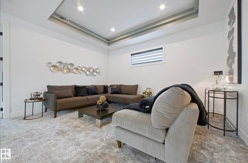 Spacious living area featuring a tray ceiling with recessed lighting, large area rug, and a window with blinds - 16607 8 Street, Edmonton, AB 