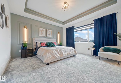 Spacious room featuring a tray ceiling with recessed lighting, an accent wall with wainscoting and wall sconces, large windows, and patterned carpeting - 16607 8 Street, Edmonton, AB 
