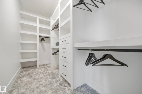 Custom closet system featuring extensive built-in shelving, multiple hanging rods, integrated drawers with dark hardware, and recessed overhead lighting - 16607 8 Street, Edmonton, AB 